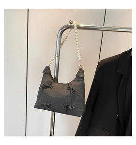 Detail of dark grey denim crescent bag with 3D bows and white pearl bead handle