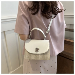 Detail of hand-woven straw crossbody bag with white leather flap and silver keyhole lock