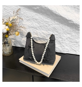 Detail of dark gray denim tote with bow accents and elegant white pearl handle