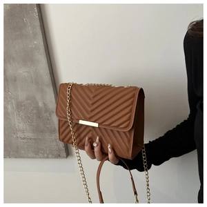 Detail of brown chevron quilted crossbody bag with gold chain strap and metal lock