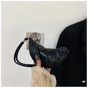 Detail of a black croissant mini bag with segmented stitching and smooth leather finish
