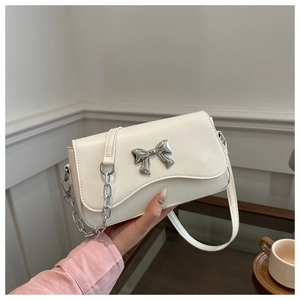 Detail of white wave flap shoulder bag featuring a silver metal butterfly clasp and chain