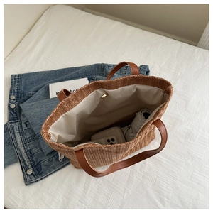 Detail view of large straw tote bag with brown PU handles and spacious interior layout