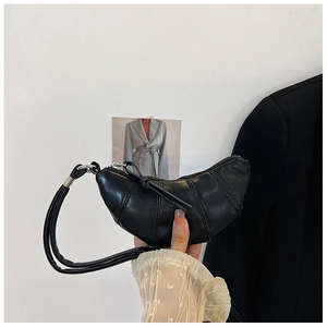 Detail of a black mini croissant bag featuring silver rings and vertical stitching