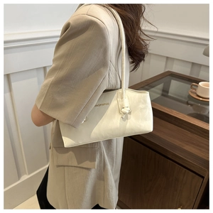Gros plan du sac à bandoulière crème avec nœud décoratif et inscription dorée chic