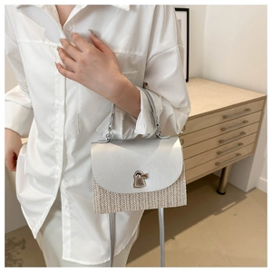 Detail of mini straw crossbody bag with silver metallic flap and vintage metal clasp