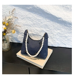 Detail of dark blue denim tote bag with black bows and elegant white pearl handle