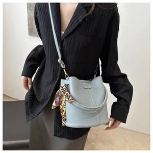 Details der hellblauen Beuteltasche mit Lederstruktur und buntem Seidenschalgriff