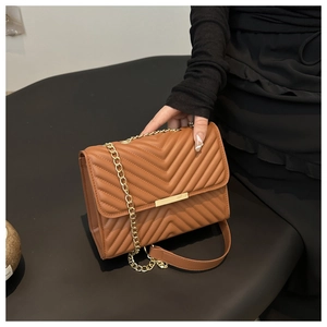 Detail of brown quilted faux leather crossbody bag with elegant gold metal clasp and chain