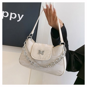 Détail du sac crème texture marbre avec boucle papillon argentée et chaînes en métal