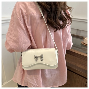 Detailed view of a white butterfly crossbody bag with silver buckle on a pink shirt