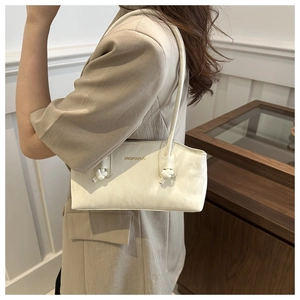 Détail d'un sac sous l'aisselle en similicuir blanc crème avec bandoulière à nœud unique