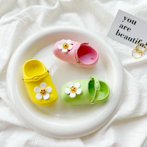 Detail of pink, yellow and green mini clog phone grips with cute smiley sun flower charms