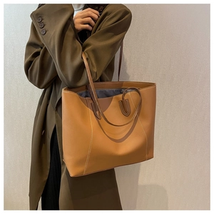 Close-up of brown tote bag featuring white contrast stitching and smooth leather texture