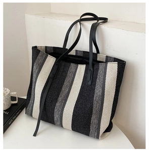 Close-up of thick woven canvas texture and black handles on the striped tote bag