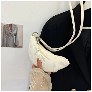 Detail of a creamy white mini crescent horn bag with vertical stitching and metal zipper