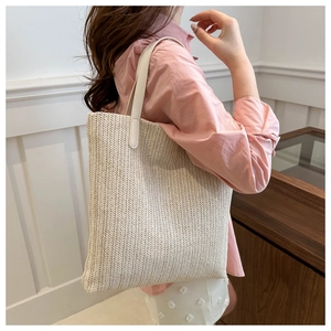Detailed close-up showing the woven herringbone texture and beige leather strap of tote