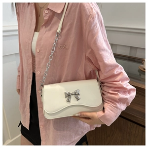 Detail of white PU leather crossbody bag featuring a silver butterfly buckle and chain strap