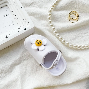 Detail of white mini clog phone grip with a yellow smiley face flower on a linen surface