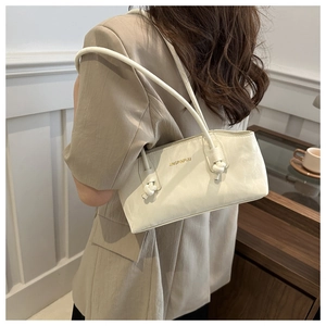 Détail d'un sac à bandoulière plissé beige avec lettrage doré et bandoulière à nœuds
