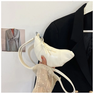 Detail of a creamy white half-moon croissant bag with vertical stitching and smooth PU leather