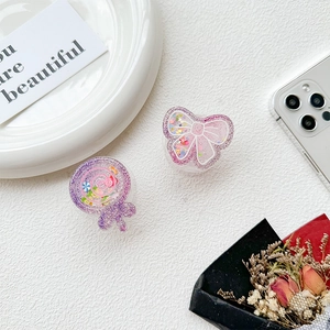 Macro detail of lollipop and bow-shaped liquid quicksand glitter phone sockets on a surface