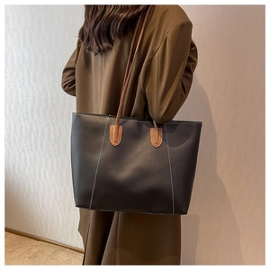 Detail of contrast stitching and brown leather handles on a large grey tote bag