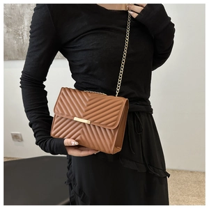 Detail of caramel brown chevron quilted bag with gold chain strap and metal clasp