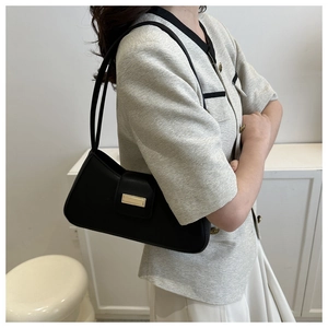 Detailansicht einer schwarzen minimalistischen Schultertasche mit goldener Metallschnalle
