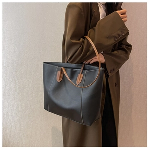 Large black leather tote bag with white stitching and dual brown shoulder straps