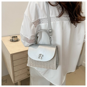 Detail of silver metallic leather flap and natural woven texture on summer square bag