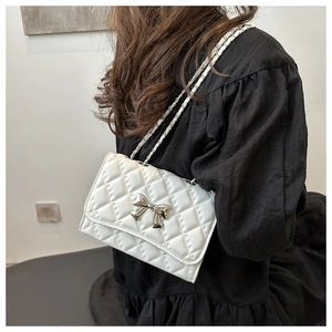 Close-up of white quilted chain bag with silver bow clasp and elegant metallic strap