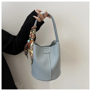 Detailansicht der hellblauen Eimertasche mit Litschi-Muster und dekorativem Seidenschal