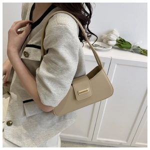 Detailansicht einer beigen minimalistischen Baguette-Tasche mit goldener Metallschnalle