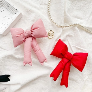 Dettaglio del supporto per telefono a fiocco in peluche rosa e rosso con nastri