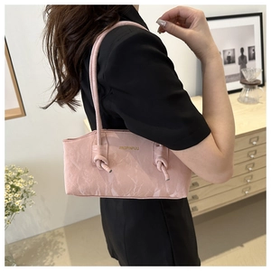 Gros plan sur un sac rose texture marbre avec bandoulière à nœuds porté par un mannequin