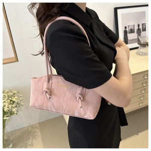Détail du sac à bandoulière rose texturé avec un design de sangle nouée très élégant