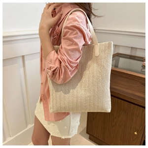 Detail of cream woven tote bag featuring fine texture and soft leather handles
