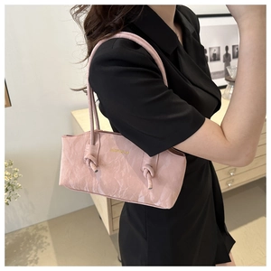 Détail du sac bandoulière rose clair avec texture marbrée et nœud décoratif élégant