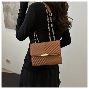 Detail of brown V-quilted faux leather bag with gold chain strap and metal lock
