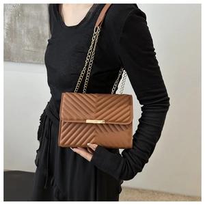 Detail of a brown chevron quilted crossbody bag with gold metal chain strap for women