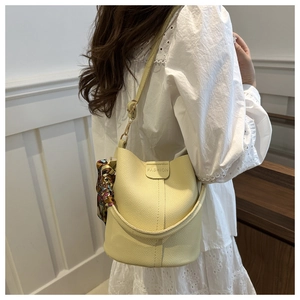 Detail of yellow bucket bag with lychee leather texture and colorful silk scarf accent