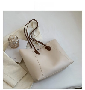Detail of minimalist cream tote bag with dark brown straps and matte faux leather texture