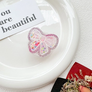 Detail of pink butterfly phone grip with heart sequins and glitter on white tray