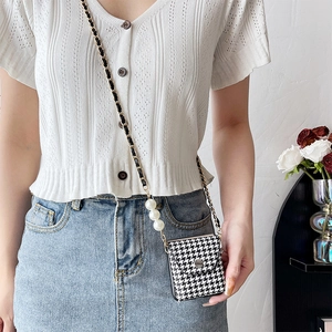 Detail of houndstooth crossbody phone case with metal chain and large pearl accents