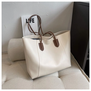 Macro shot of minimalist cream tote bag with deep brown handles and textured PU leather