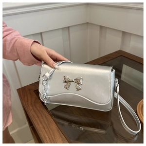 Detail of silver metallic handbag featuring butterfly bow buckle and chain strap
