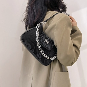 Sac bandoulière noir avec motif de vagues et boucle papillon argentée sur modèle