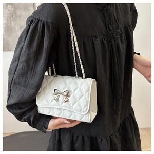 White quilted shoulder bag featuring a silver metal bow and leather chain strap