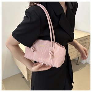 Détail du sac bandoulière rose clair avec texture plissée et design de bandoulière nouée